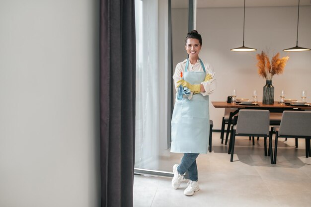 Rotina doméstica. Dona de casa sorridente em pé de avental na cozinha