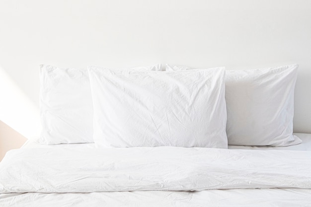 Roupa de cama branca em uma cama em um quarto branco