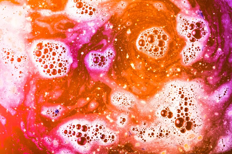 Foto grátis roxa; espuma laranja e vermelha após bomba de banho de cor dissolvendo em água