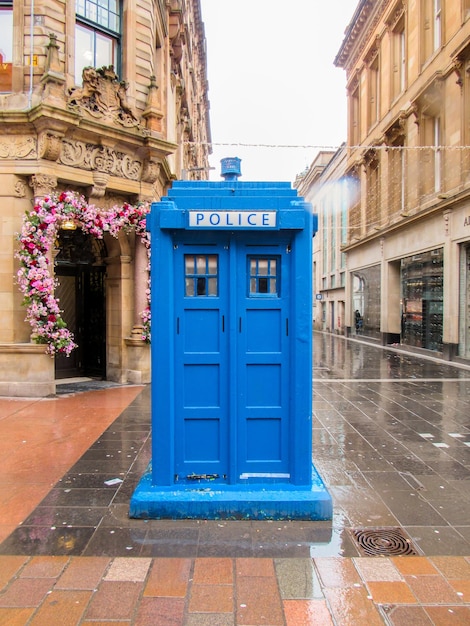 Rua com caixa de polícia azul em Glasgow Reino Unido Velhos edifícios tradicionais tempo nublado