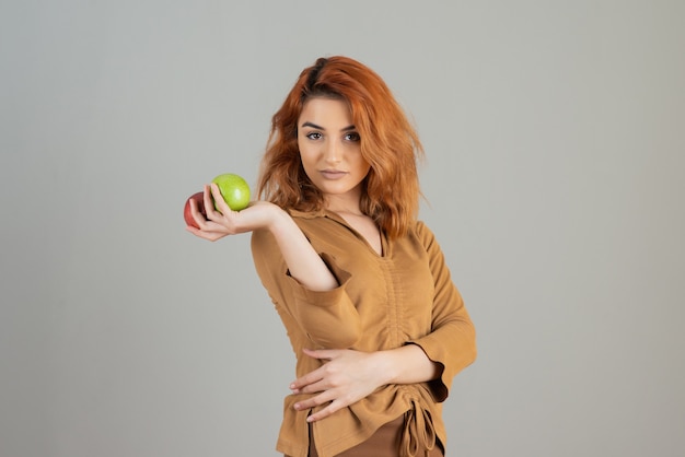 Foto grátis ruiva jovem confiante segurando maçãs frescas e olhando para a câmera.