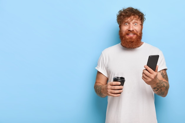 Ruivo alegre posando com seu telefone