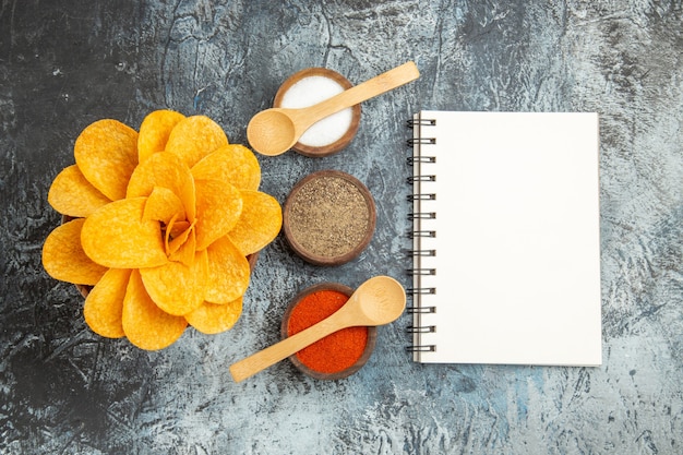 Saborosas batatas fritas decoradas em forma de flores, especiarias diferentes com colheres em fundo cinza