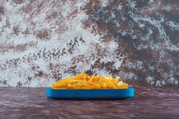 Foto grátis saborosas batatas fritas em uma placa de madeira, sobre a mesa de mármore.