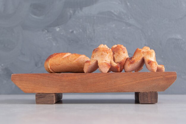 Saborosas salsichas grelhadas na placa de madeira.