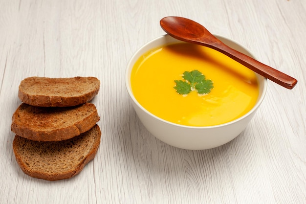 Saboroso creme de sopa de abóbora com vista frontal, com textura de pão preto no espaço em branco