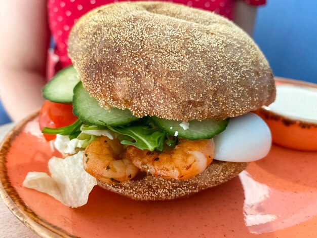 Saboroso hambúrguer com camarão, ovo e pepino fresco. sanduíche em um prato