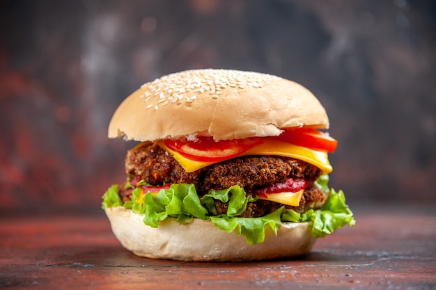 Saboroso hambúrguer de carne com queijo e salada de frente no fundo escuro