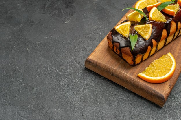 Saborosos bolos decorados com laranjas e chocolate na tábua de cortar na mesa preta