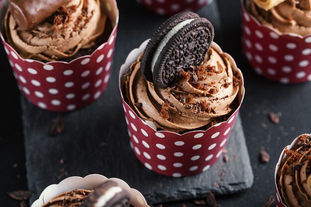 Saborosos cupcakes de muffins de chocolate com creme de manteiga decorados em copos. Fechar-se