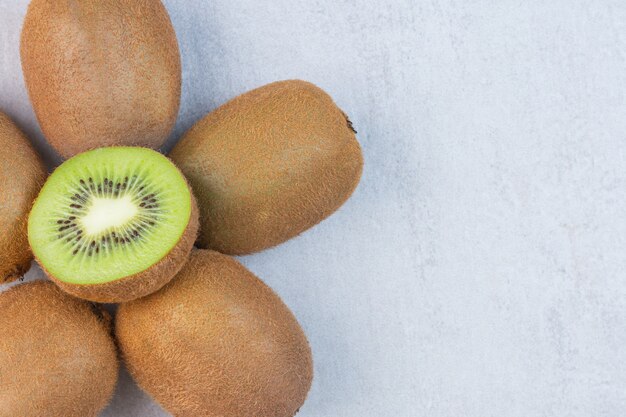 Saborosos kiwis inteiros e fatiados na mesa de mármore.