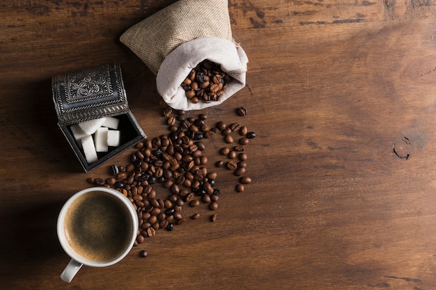 Saco com grãos de café perto de caixa de açúcar e copo