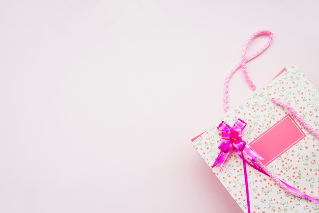 Saco de compras de aniversário com laço rosa no fundo rosa