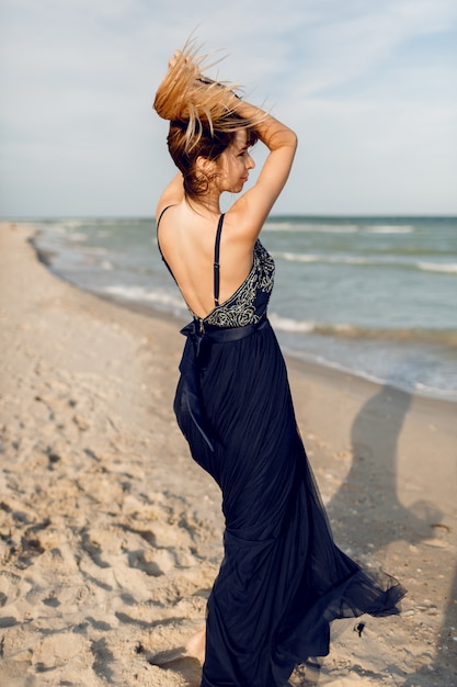 Foto grátis saindo de mulher graciosa em elegante vestido azul longo, brincando e se divertindo na praia tropical. férias