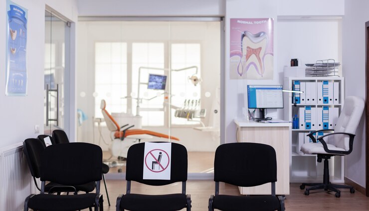 Foto grátis sala de espera na clínica sem ninguém dentro, escritório da frente com novo normal tendo sinal na cadeira para distância social em pandemia de coronavírus