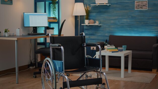 Sala de estar vazia com cadeira de rodas para ajudar com deficiência crônica e lesões. Ninguém no espaço com objeto de transporte para dar suporte ao paciente e ajudar na acessibilidade. Recuperação física