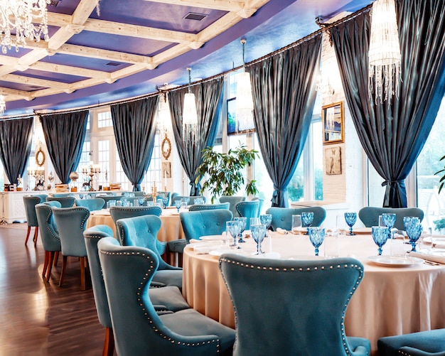 Sala de restaurante com cadeiras azuis e óculos azuis em cima da mesa