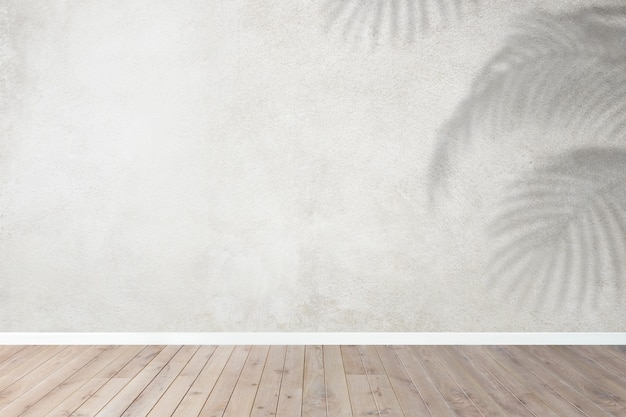 Sala vazia com parede cinzenta e sombra de folhas tropicais