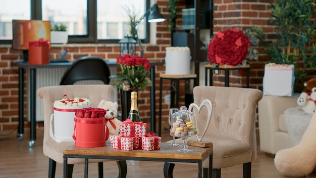 Sala vazia decorada pelo namorado com presentes românticos de dia dos namorados para namorada comemorar aniversário de romance em casa. Sala de estar com rosas vermelhas na mesa. Conceito de presente de dia dos namorados