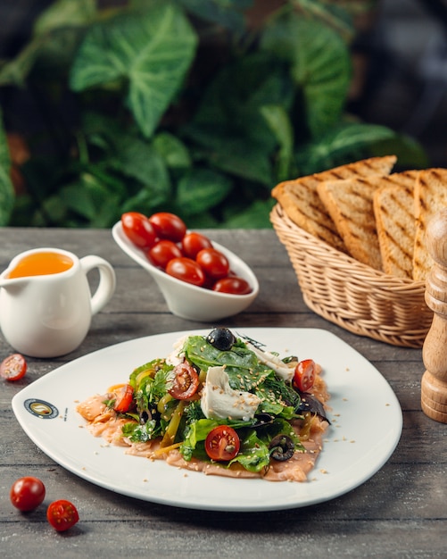 Salada Caesar com ervas, tomate cereja e torradas de pão.