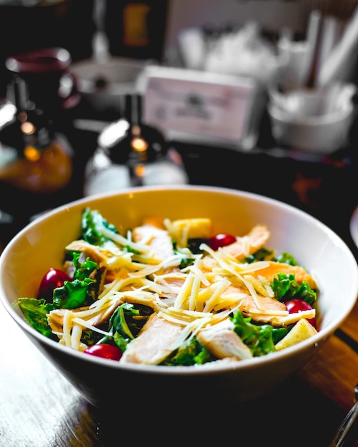 Salada caesar com frango e tomate cereja em uma tigela em cima da mesa