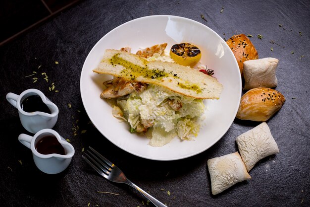 Salada caesar frango alface tomate limão parmesão anchovas pãezinhos vista lateral