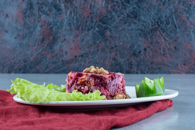 Salada de beterraba, cenoura e couve-flor. guarnecido com nozes, pepinos e folha de alface no mármore.