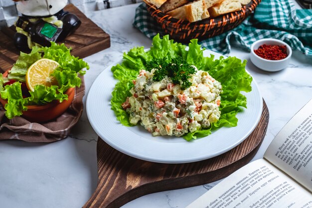 Salada de capital vista frontal em alface com pão e uma fatia de limão em cima da mesa