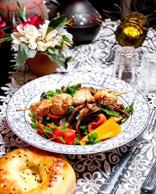 Salada de carne com pimentão, salsa e azeite coberto com pedaços de frango no espeto