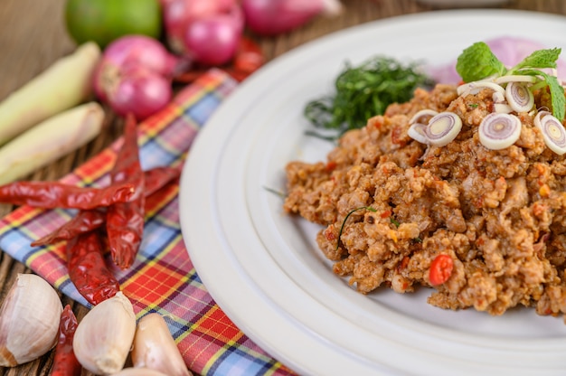 Foto grátis salada de carne de porco picada picante em um prato branco com cebola roxa, capim-limão, alho, feijão, folhas de limão kaffir e cebolinha