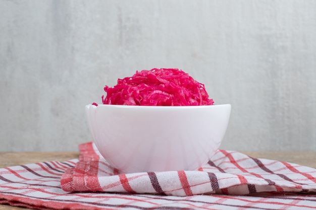 Salada de chucrute vermelho em tigela branca com toalha de mesa