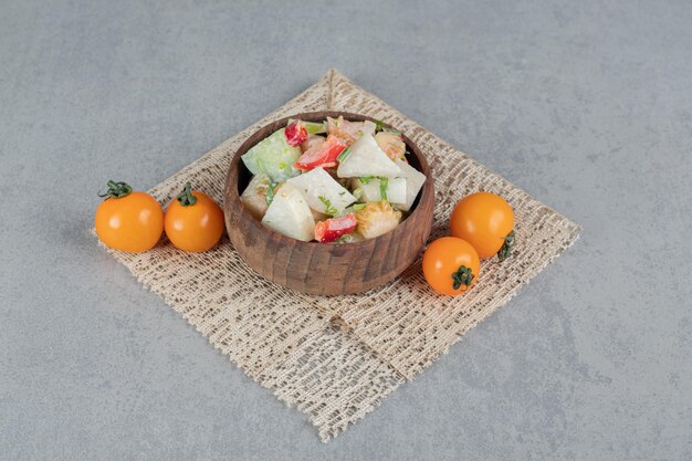 Salada de legumes com ingredientes mistos em uma xícara de madeira.