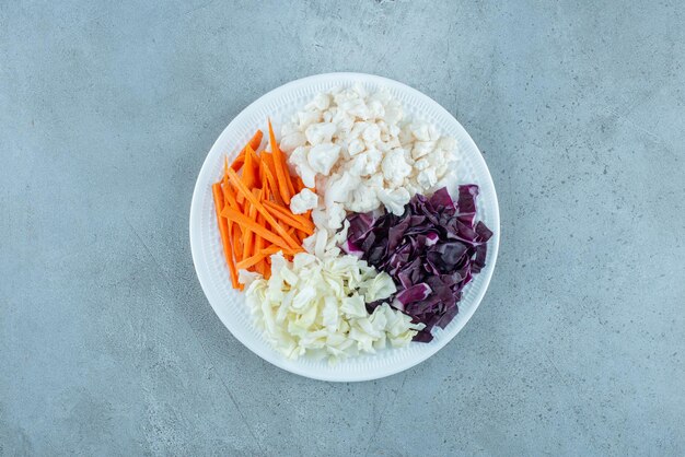 Salada de legumes com repolho branco e roxo picado e acompanhamentos.