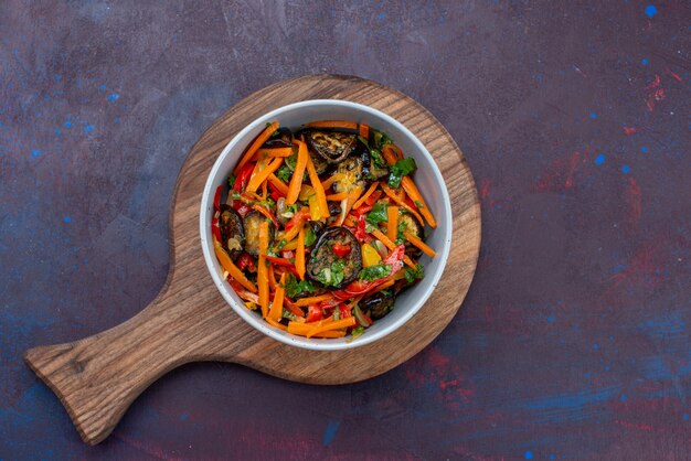 Salada de legumes em fatias de vista de cima dentro do prato na mesa escura