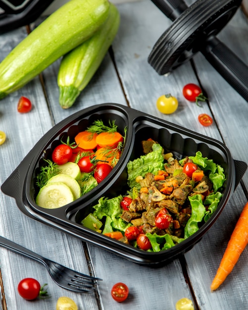 Salada de legumes em tanque de plástico separado