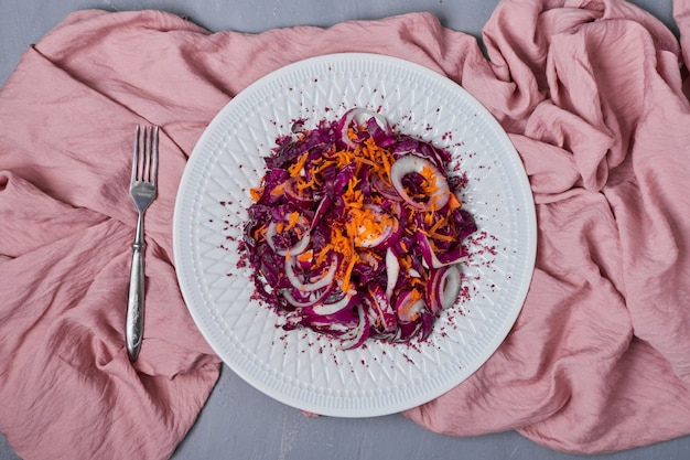 Foto grátis salada de legumes em um prato branco no azul