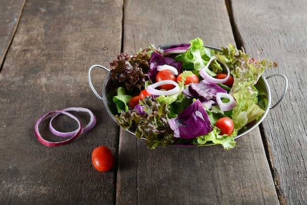 Salada de legumes frescos na tigela com fundo de madeira velho e rústico.