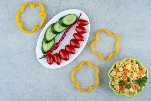 Salada de legumes na chapa branca com macarrão no fundo de mármore. Foto de alta qualidade