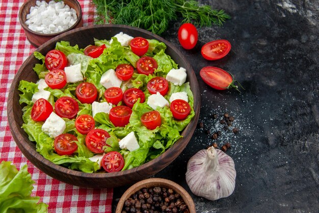 Salada de legumes vista frontal com tomates de queijo fatiados e temperos em fundo escuro comida refeição dieta almoço cor