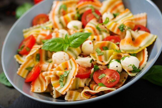 Salada de macarrão colorido farfalle com tomate, mussarela e manjericão.