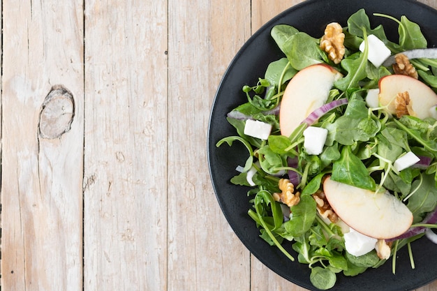 Foto grátis salada de outono com maçãs e nozes em mesa de madeira