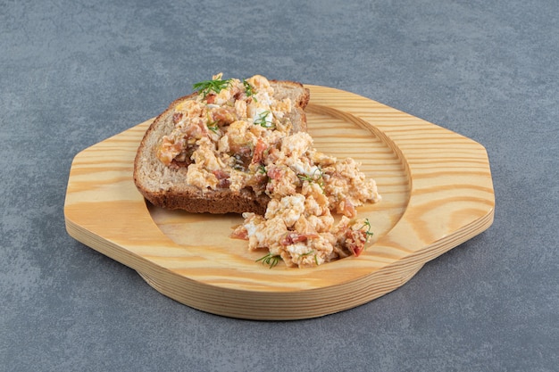 Salada de ovo e pão na placa de madeira.