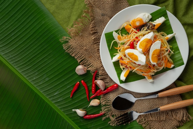 Salada de papaia servida com macarrão de arroz e salada de vegetais decorada com ingredientes da comida tailandesa.