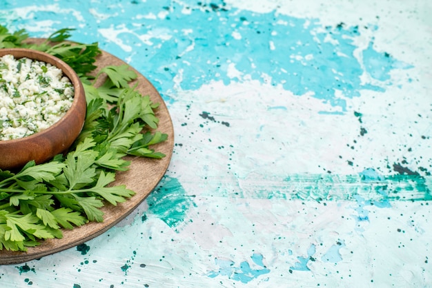 Salada de repolho fatiado fresco com verduras dentro de uma tigela marrom na mesa azul brilhante