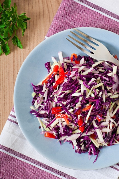 Salada de repolho roxo e branco e pimentão vermelho temperado com suco de limão e azeite de oliva em uma tigela de madeira