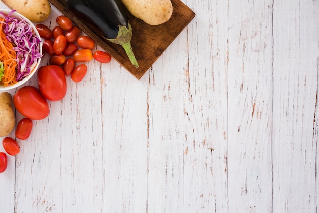 Foto grátis salada de repolho; tomates; batatas e beringela na esquina da mesa branca