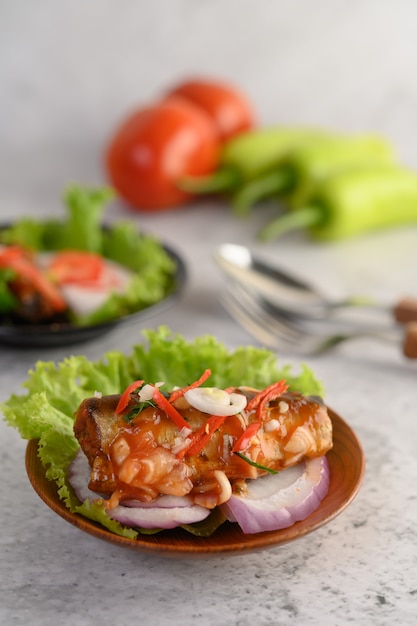 Salada de sardinha em conserva picante apetitosa com molho picante em uma tigela de madeira