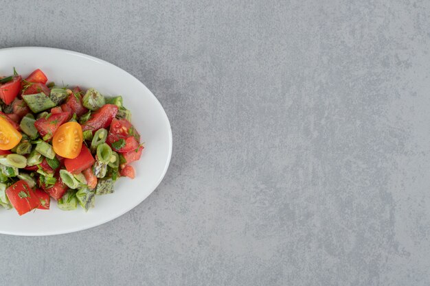 Salada de tomate cereja vermelha e feijão em um prato de cerâmica