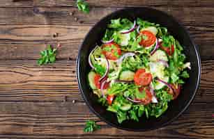 Foto grátis salada de tomate, pepino, cebola roxa e folhas de alface. menu de vitamina verão saudável. comida vegetal vegana. mesa de jantar vegetariana. vista do topo. configuração plana