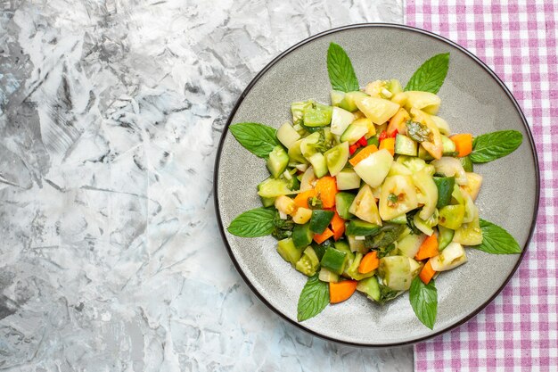 Salada de tomate verde vista de cima em prato oval toalha de mesa rosa em superfície escura